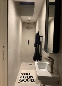 a bathroom with a sink, mirror and towel on the floor next to it's door