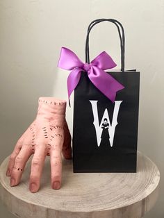 a halloween treat bag and glove sitting on top of a wooden table with a purple bow