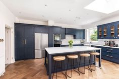 a kitchen with blue cabinets and stools next to an island in the middle of the room