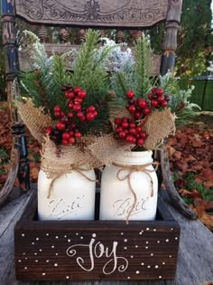 two mason jars filled with berries and greenery are sitting on a chair