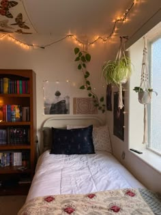 a bedroom with a bed, bookshelf and hanging plants on the wall above it