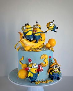 a three tiered cake with minion figurines on top