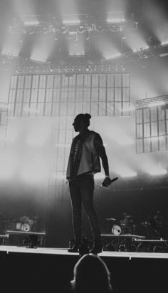 a man standing on top of a stage in front of a crowd at a concert