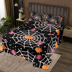 a bed covered in black and orange spider webs with pumpkins on the bottom