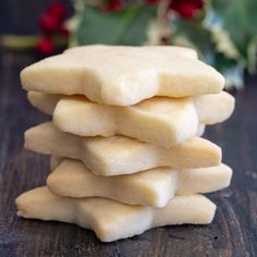 a stack of shortbread cookies sitting on top of a wooden table next to holly