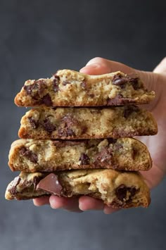 a person holding three chocolate chip cookies in their hand