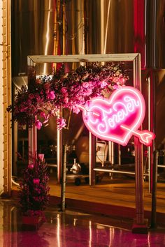 a heart shaped neon sign sitting on top of a table