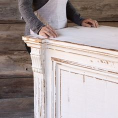 a woman in an apron is standing at the top of a white cabinet with wood planks