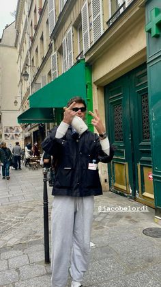 a man is standing on the street talking on his cell phone and drinking from a paper cup