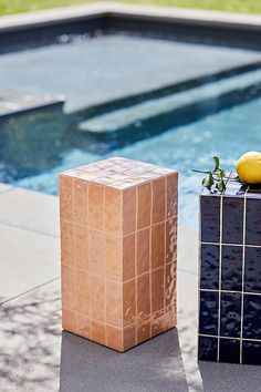 an orange sitting on top of a block next to a pool