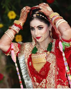 a woman dressed in red and gold is holding her hands up to her head with both hands