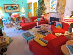 a living room filled with red couches and colorful furniture in front of a fire place