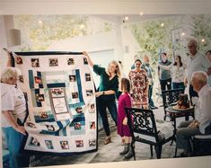 a group of people holding up a large quilt