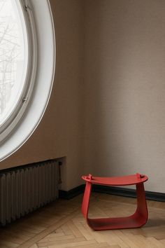 a red bench sitting in front of a round window next to a radiator