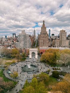 an aerial view of a park with people walking around it and buildings in the background