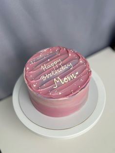 a pink birthday cake sitting on top of a white plate