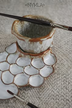 two bowls with spoons sitting on top of each other next to an artist's brush