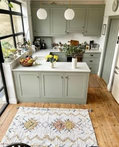 a kitchen with green cabinets and white counter tops, an area rug on the floor