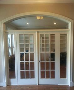 an empty room with french doors and hard wood flooring on the side walk way