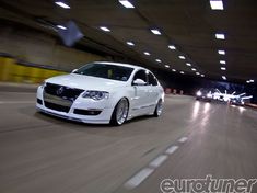 a white car is driving down the street at night in an underground parking garage area