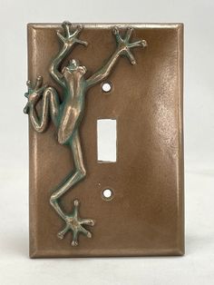 a decorative light switch cover with a frog on it's back and arms in the air