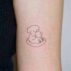 a small tattoo of a dog holding a teddy bear in its paws on the arm