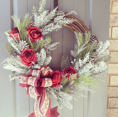 a wreath with red roses and greenery on the front door