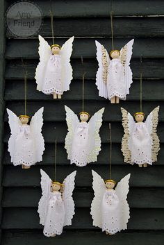 six angel ornaments hanging from strings on a wall