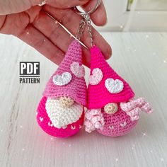 two crocheted pink and white keychains are being held by someone's hand