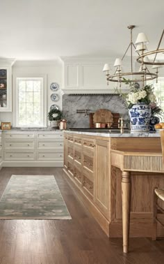 a large kitchen with wooden floors and white cabinets, along with an area rug on the floor