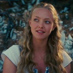 a woman with long hair and blue eyes is looking at the camera while wearing a white dress