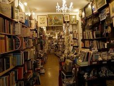 a room filled with lots of books next to a chandelier