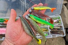 a person holding several different types of fishing lures in their hand, with one being held by the other