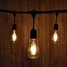 three light bulbs hanging from a wooden wall