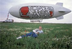 a man sitting in the middle of a field next to an air plane that has been painted on it