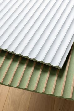 a close up view of a metal roof on a wooden floor with green and white stripes