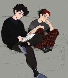 two young men sitting on a couch looking at something in front of them, one reading a paper