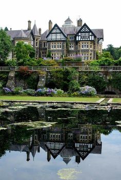 a large building sitting on top of a lush green hillside next to a lake filled with water lilies