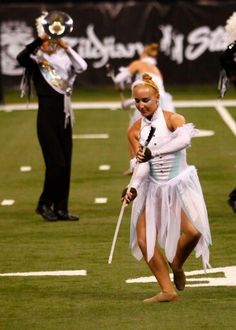 a group of people in costume on a field with marching sticks and trombones behind them