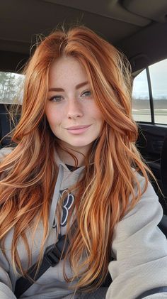 a woman with long red hair sitting in the back seat of a car looking at the camera