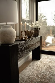 a vase sitting on top of a wooden table next to a window