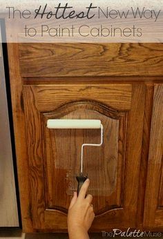 someone is painting the cabinets in their kitchen with white paint and a brown cabinet door