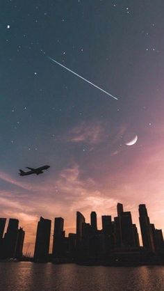 an airplane is flying in the sky over a city at night with stars and crescents