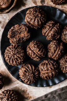 chocolate cookies on a black plate next to some nuts