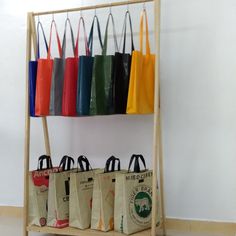 several bags are lined up on a shelf with the handles down and tote bags in different colors