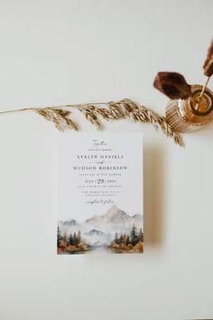 the wedding stationery is displayed next to a dried plant