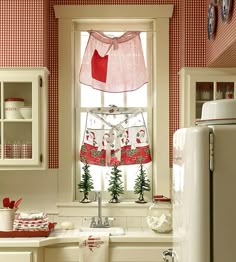 a kitchen with red and white checkered wallpaper, an old fashioned refrigerator and window