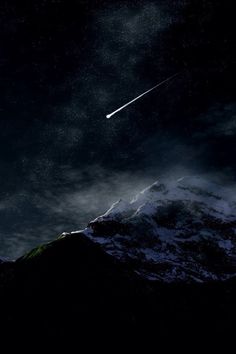 an airplane is flying in the sky over some snow covered mountains and trees at night