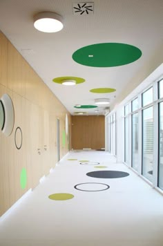 an empty hallway with green and white circles painted on the floor in front of large windows