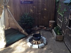 an outdoor fire pit in the middle of a backyard with a teepee tent and trees